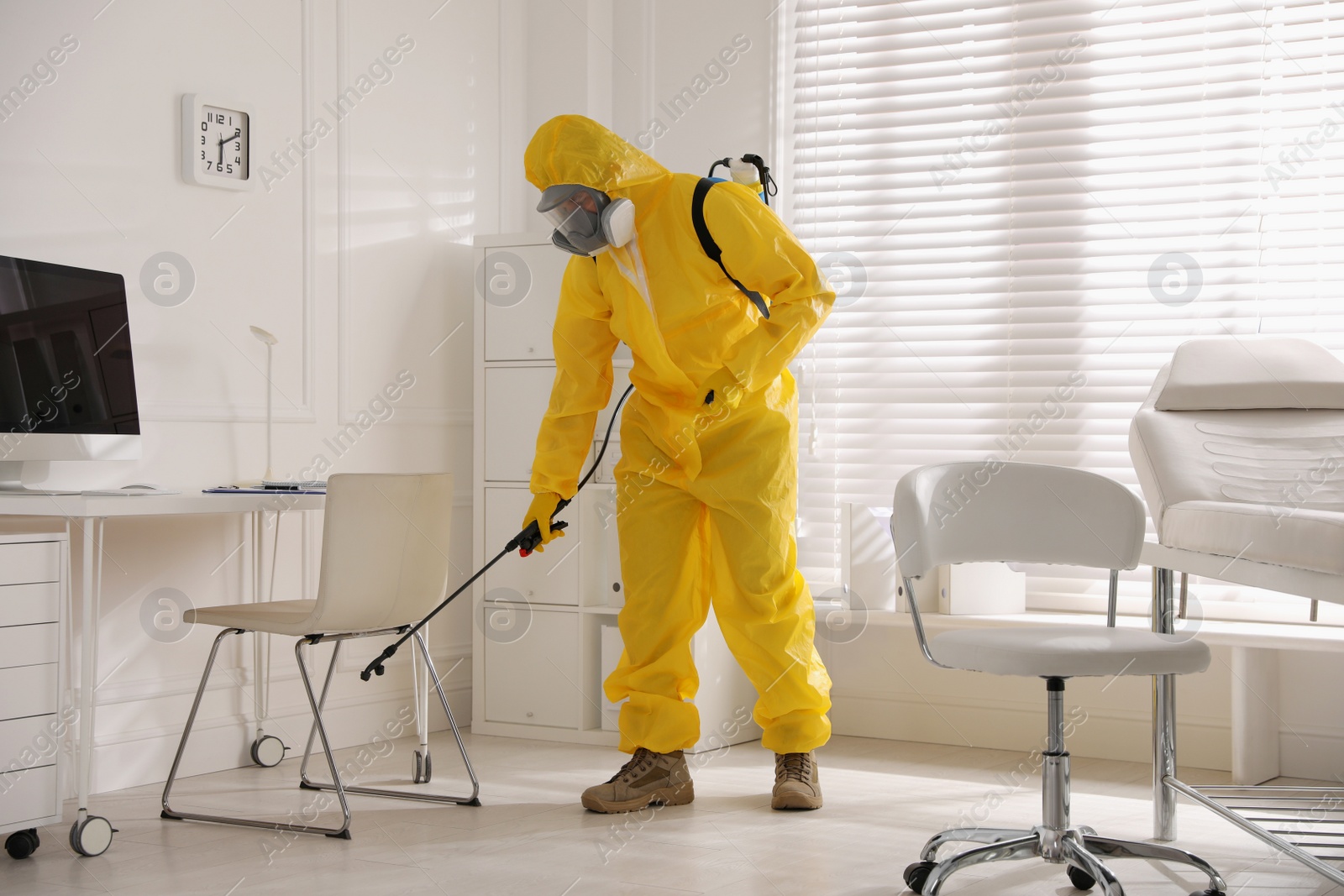 Photo of Man in protective suit sanitizing doctor's office. Medical disinfection