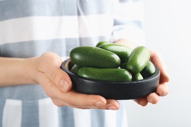 Photo of Woman holding black wooden bowl with fresh seedless avocados, closeup