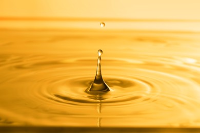 Splash of golden oily liquid with drops as background, closeup