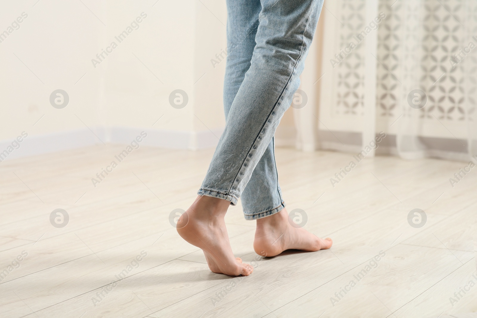 Photo of Woman stepping barefoot in room at home, closeup. Floor heating