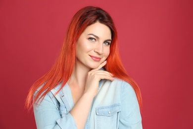 Photo of Young woman with bright dyed hair on red background