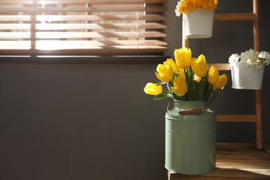 Photo of Beautiful sunlit bouquet with yellow tulips on wooden table in room. Space for text