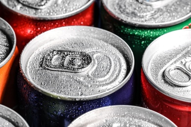 Photo of Aluminum cans of beverage covered with water drops as background, closeup