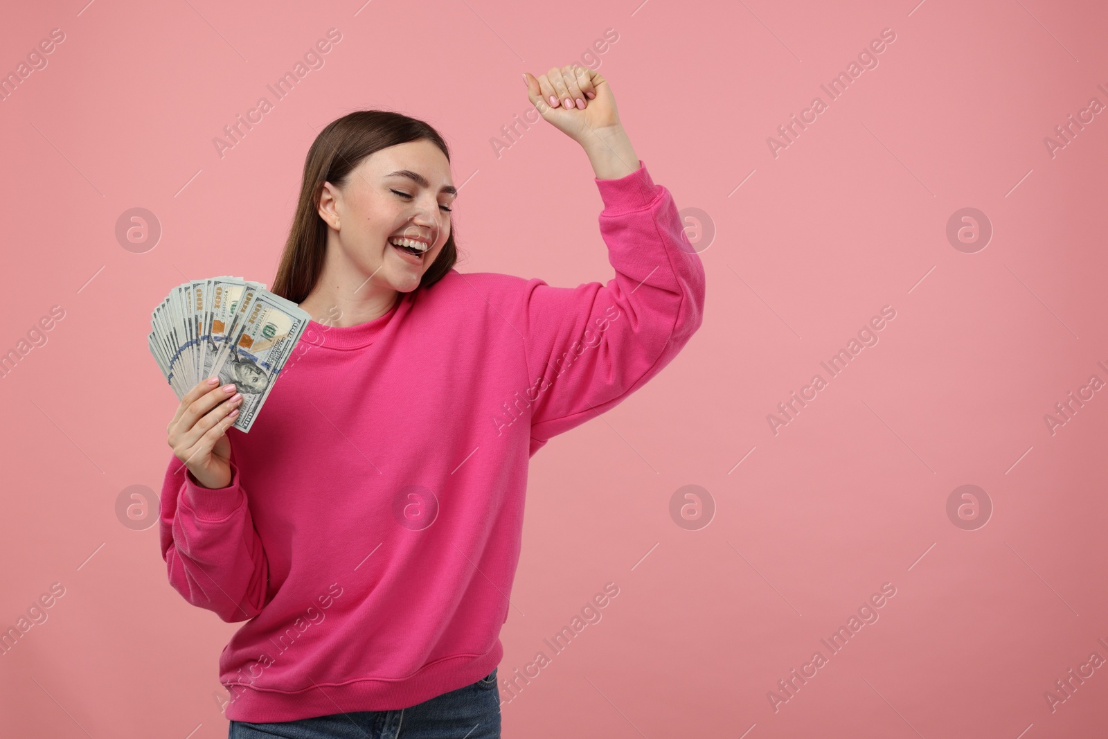 Photo of Happy woman with dollar banknotes on pink background, space for text