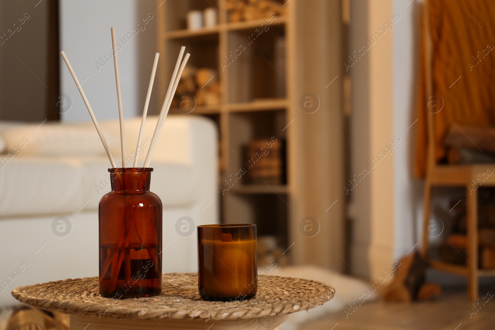 Photo of Aromatic reed air freshener and candle on wicker tray in room. Space for text