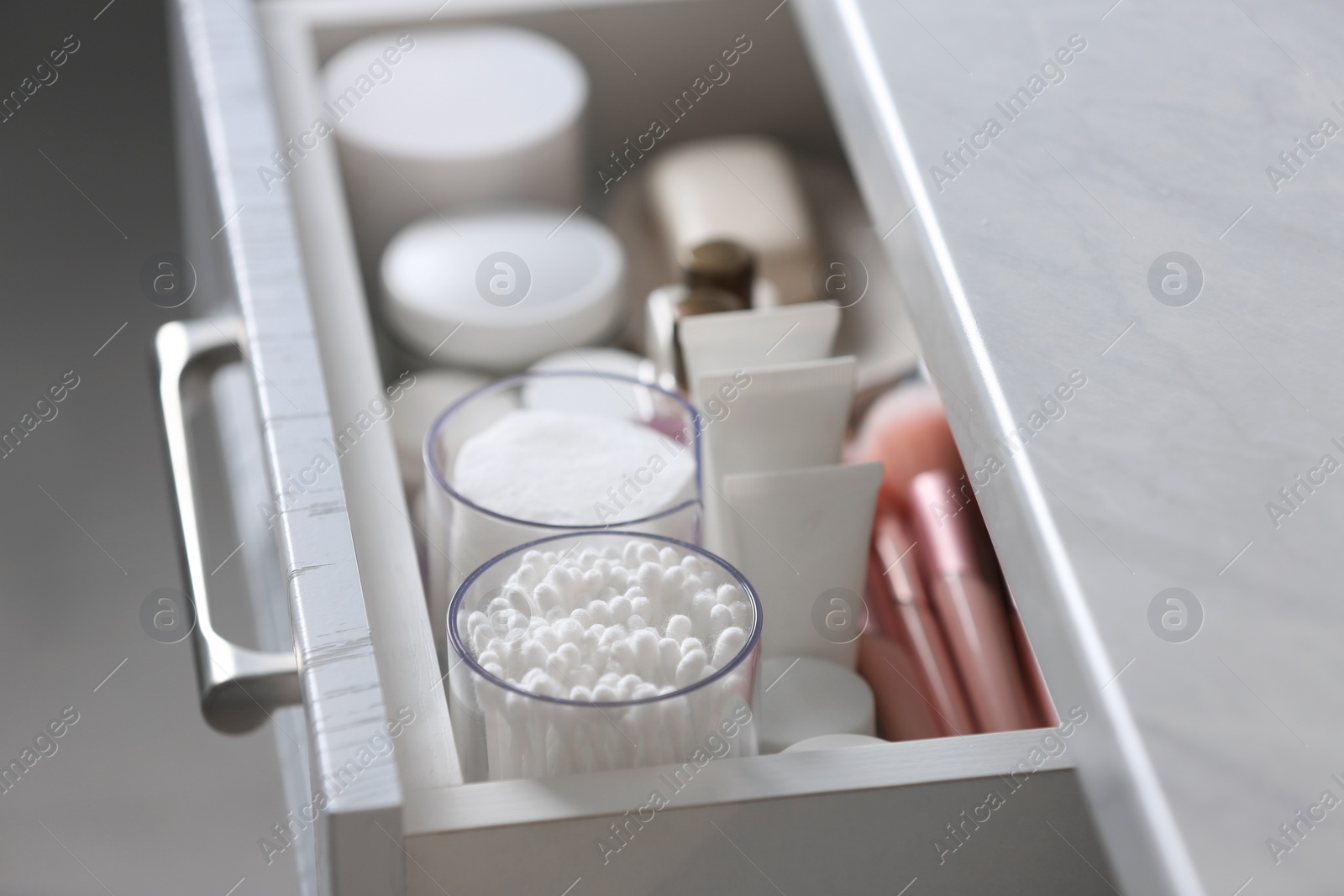 Photo of Open cabinet drawer with cotton buds and pads indoors, closeup