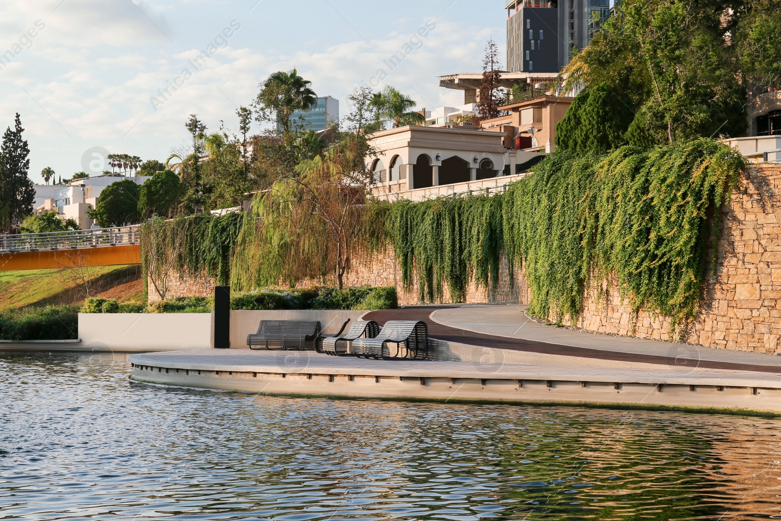 Photo of Picturesque view of park with river, bridge and wooden benches