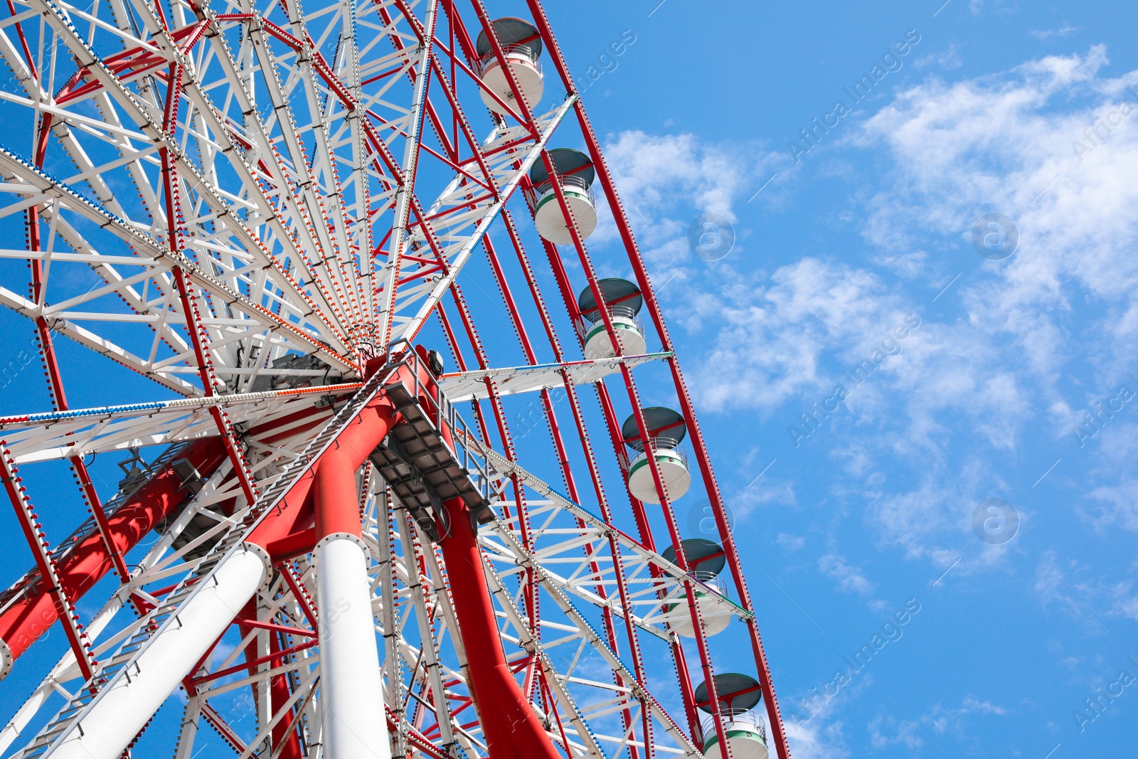 Photo of Beautiful large Ferris wheel against blue sky, low angle view