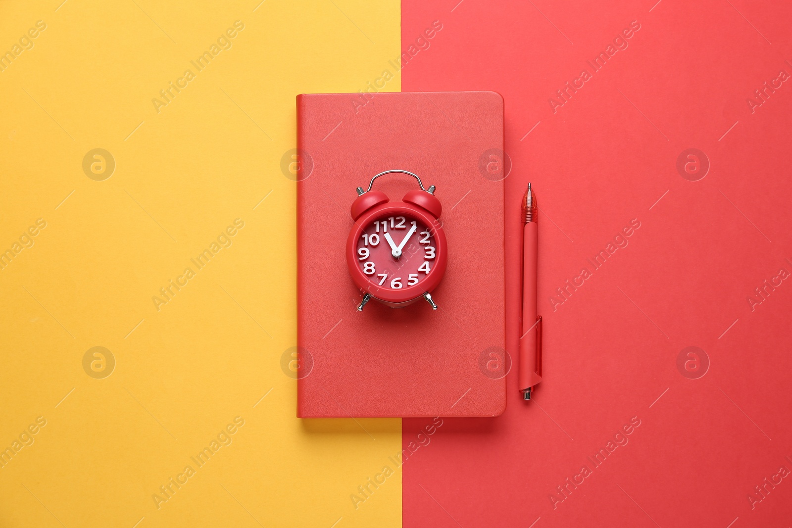 Photo of Red notebook, alarm clock and pen on color background, top view