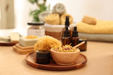 Photo of Dry flowers, loofah and jar of cream on wooden table. Spa time