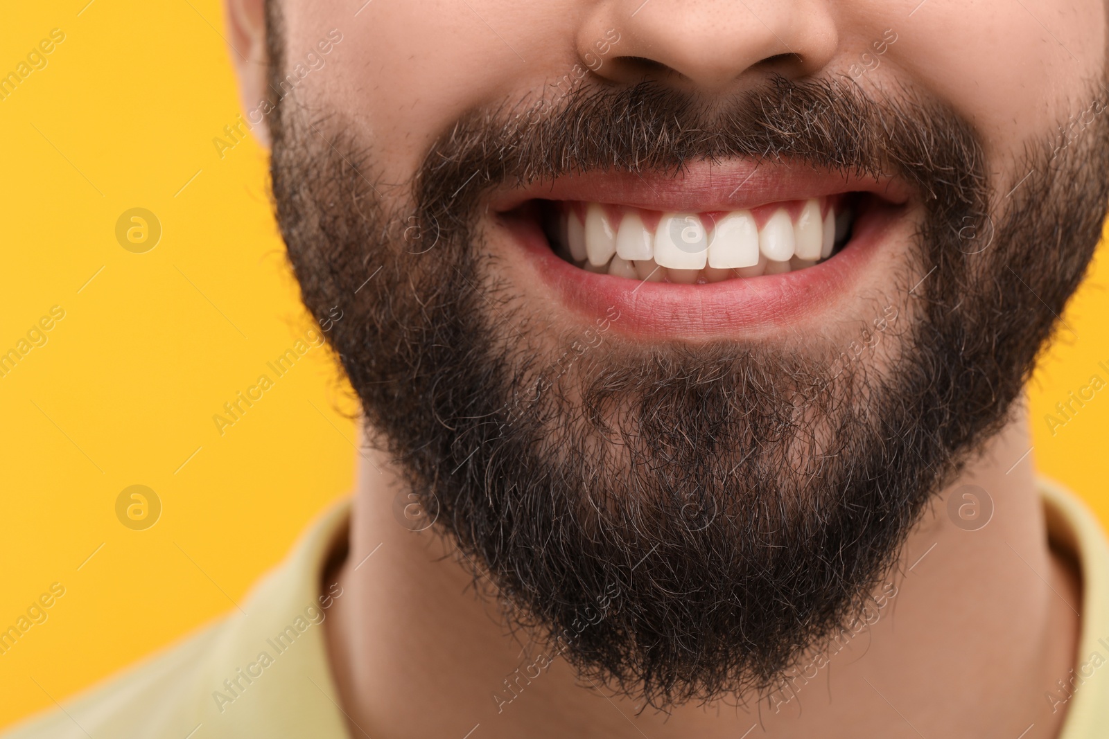 Photo of Man with clean teeth smiling on yellow background, closeup