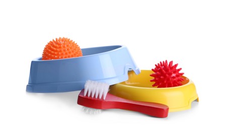 Feeding bowls, brush and dog toys on white background