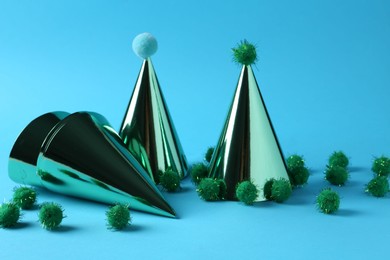 Party hats with green pompoms on light blue background