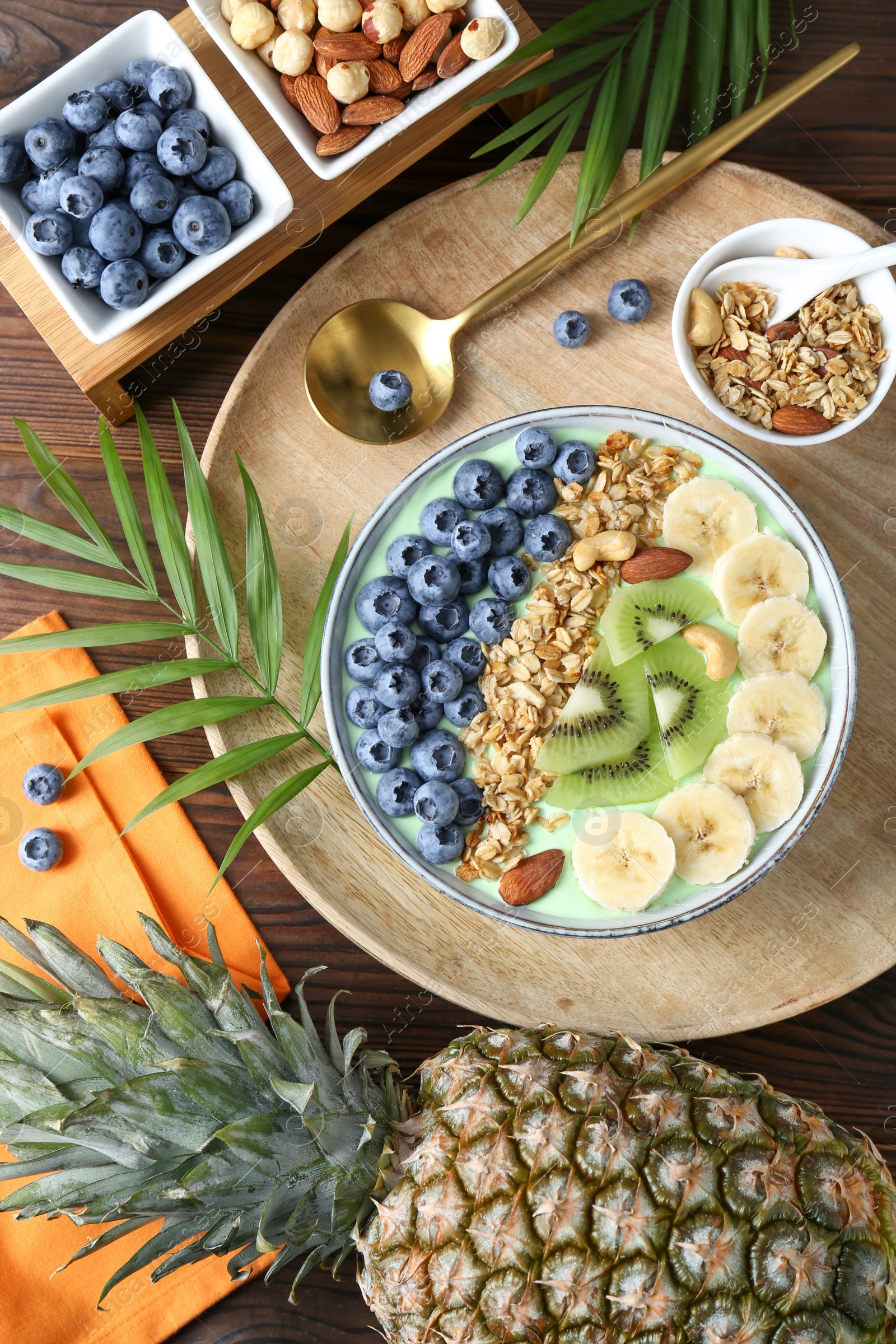 Photo of Tasty smoothie bowl with fresh fruits and oatmeal served on wooden table, flat lay