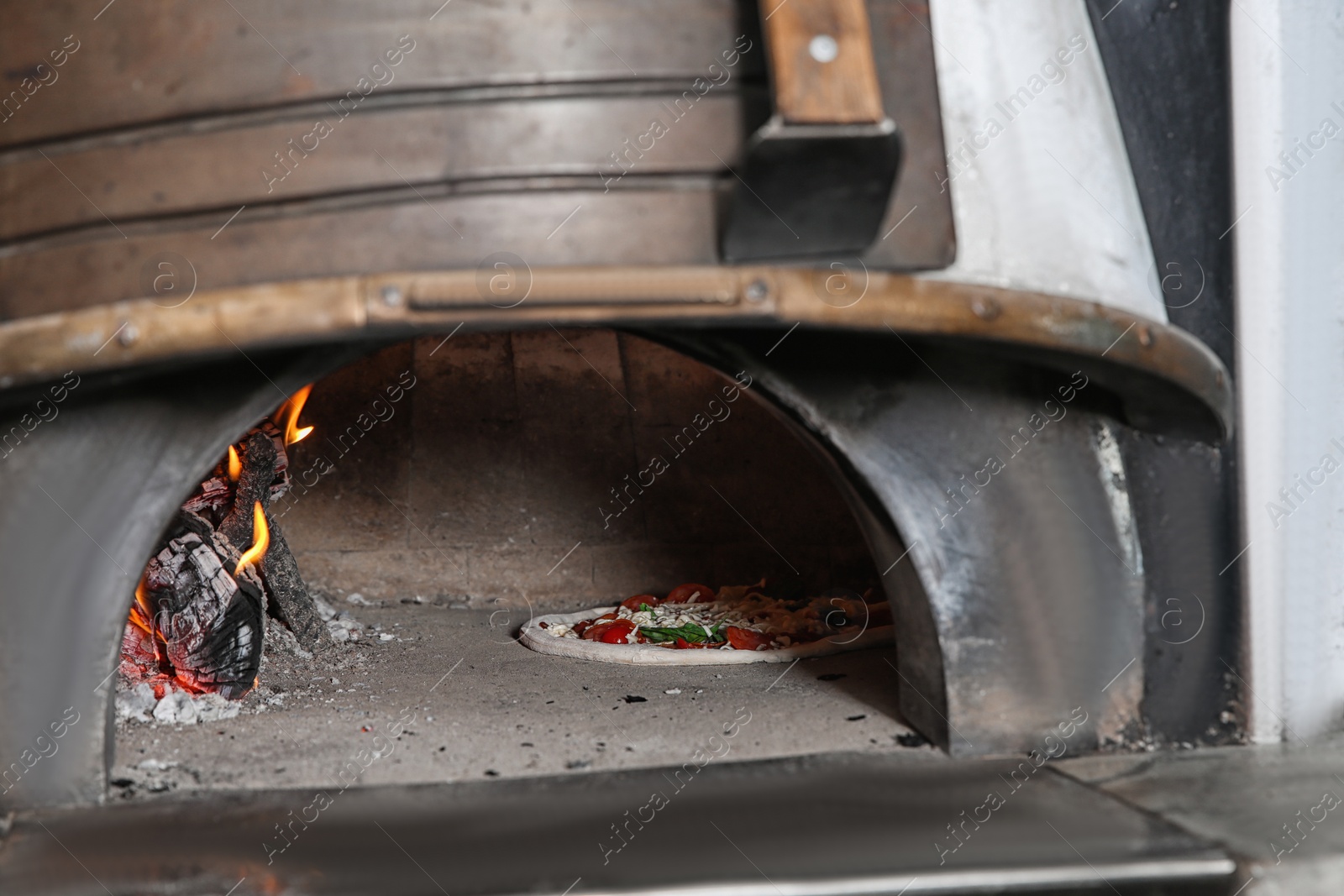 Photo of Burning firewood and tasty pizza in oven at restaurant kitchen