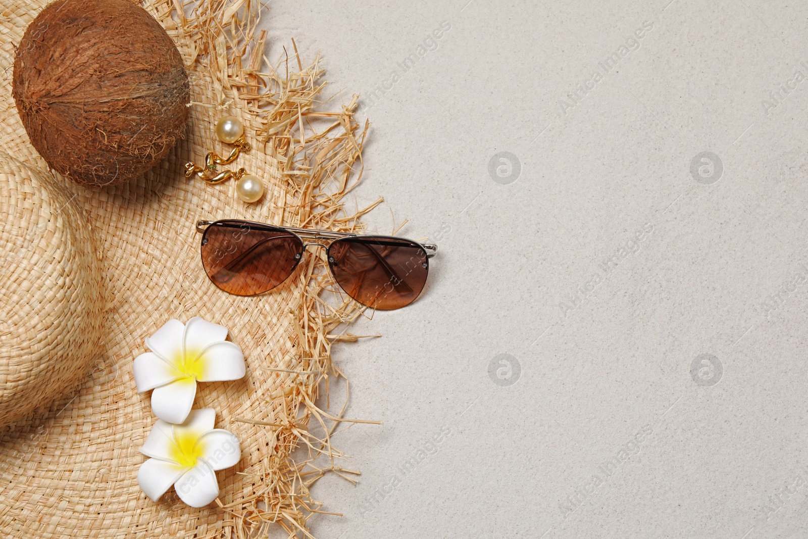 Photo of Flat lay composition with stylish sunglasses and straw hat on sand. Space for text