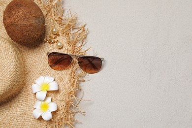 Photo of Flat lay composition with stylish sunglasses and straw hat on sand. Space for text