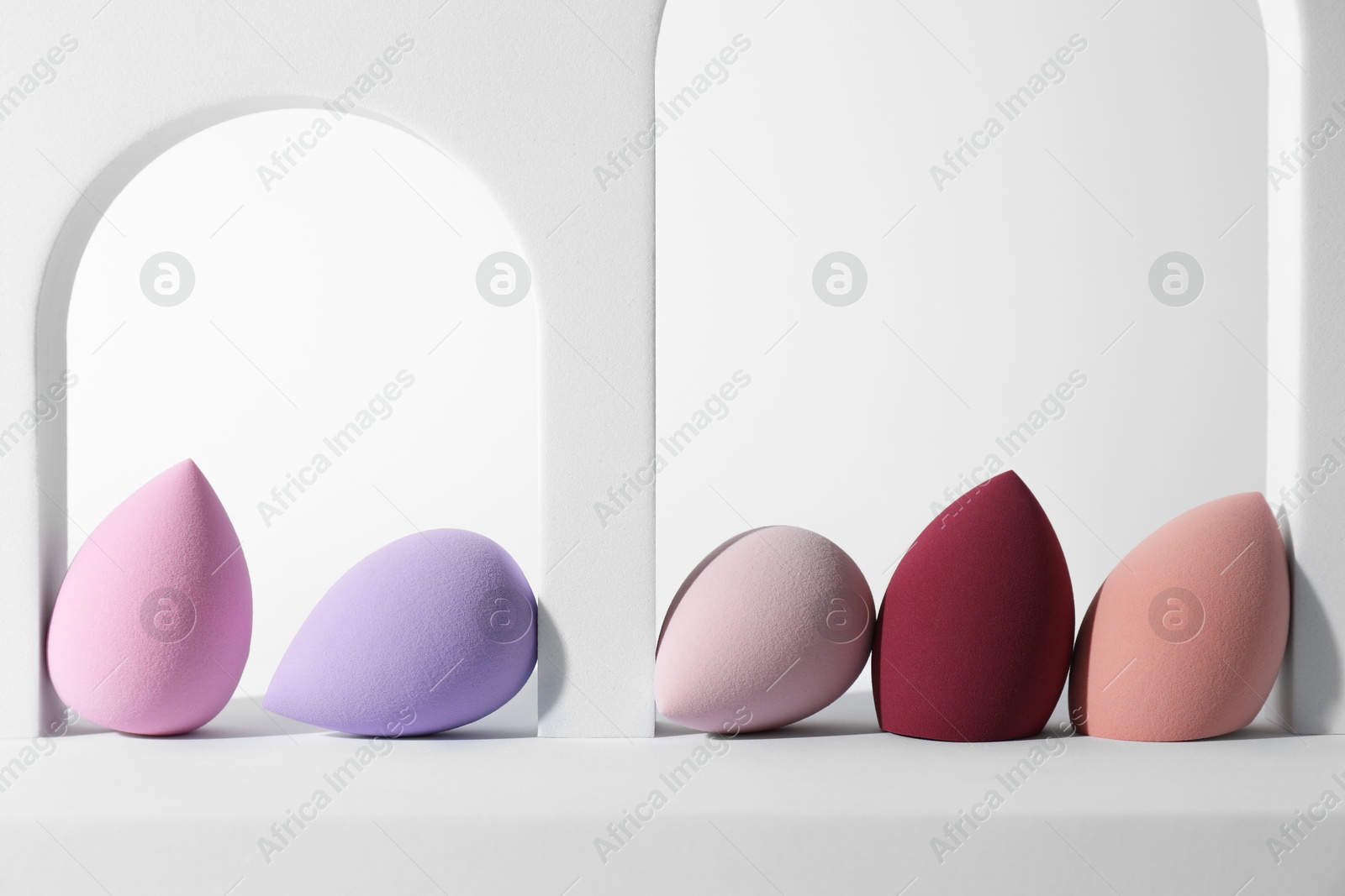 Photo of Stylish presentation of makeup sponges on white background