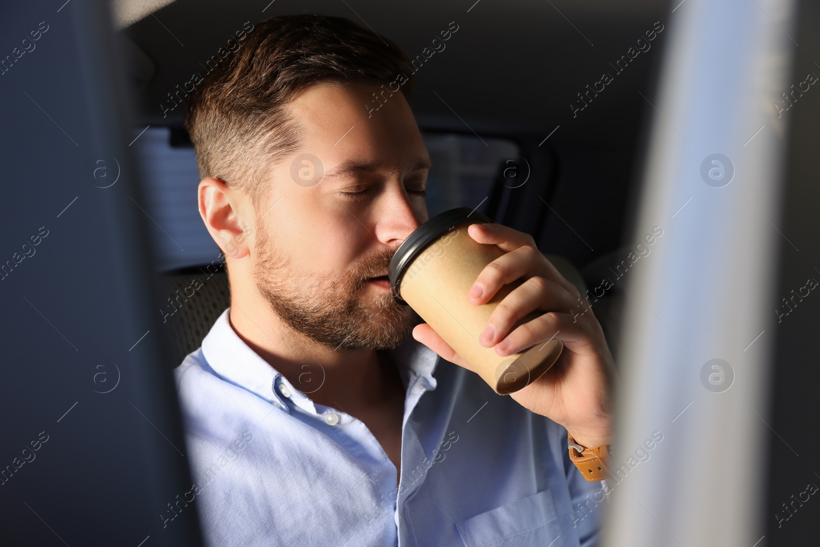 Photo of To-go drink. Handsome man drinking coffee in car