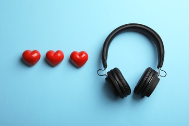 Photo of Decorative hearts and modern headphones on color background, flat lay