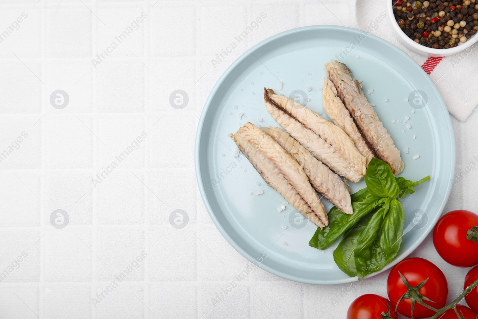 Photo of Canned mackerel fillets served on white tiled table, flat lay. Space for text