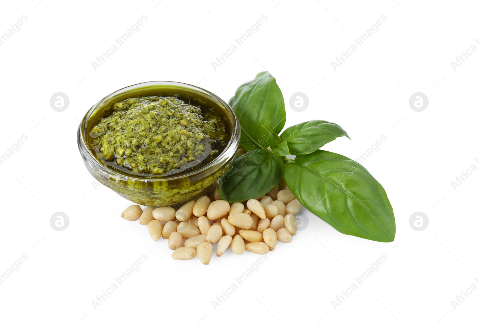 Photo of Tasty pesto sauce in glass bowl, pine nuts and basil on white background