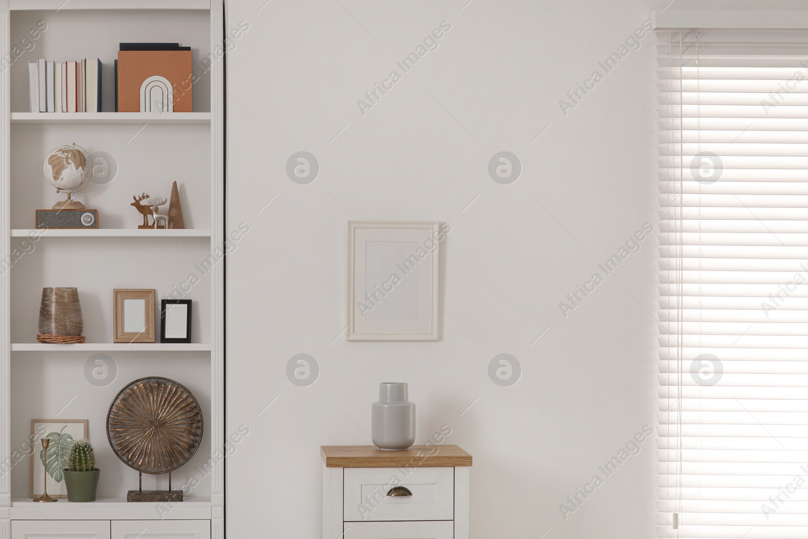 Photo of Stylish shelves with different decor elements and chest of drawers in room. Interior design