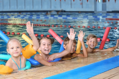 Photo of Little kids with swimming noodles in indoor pool