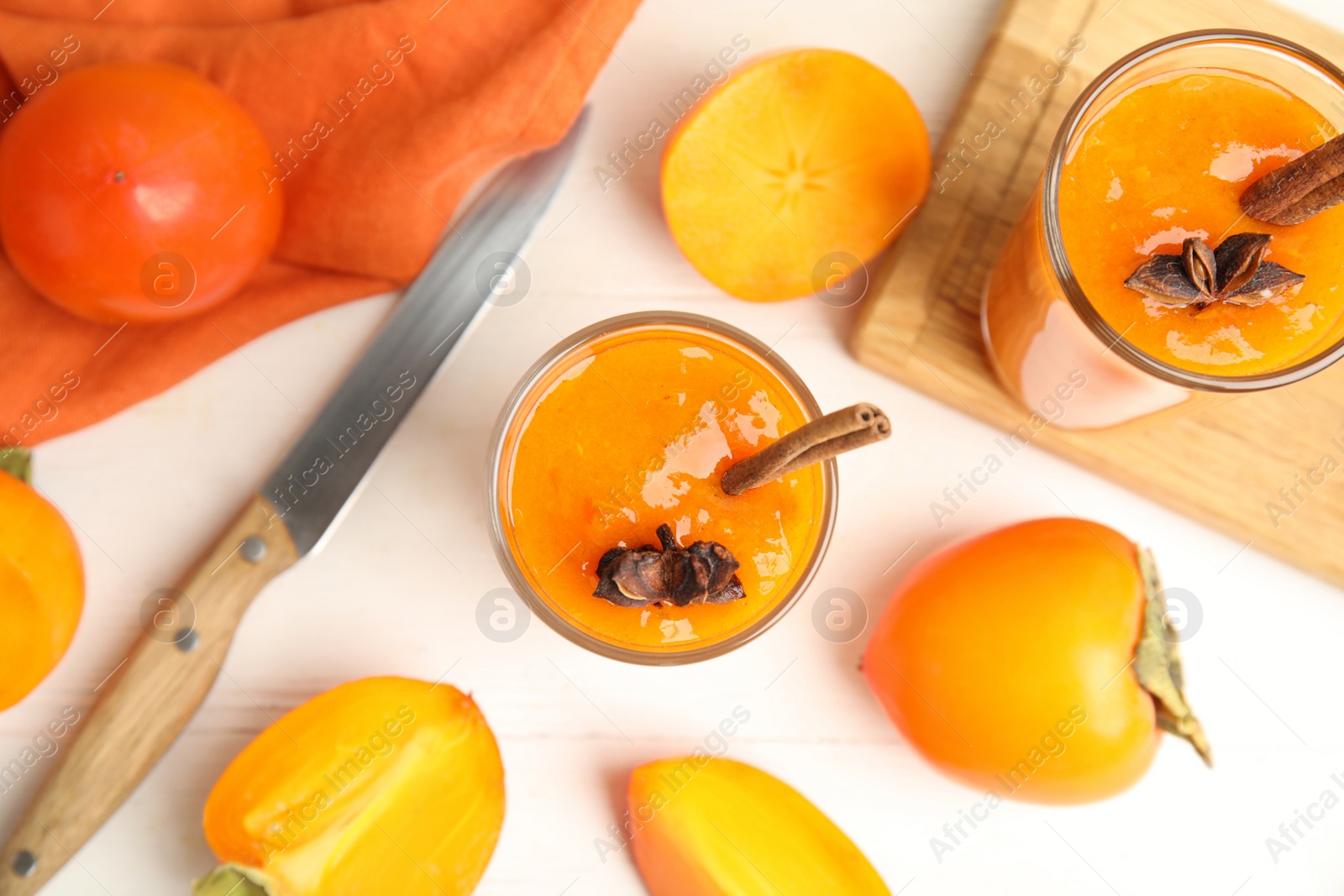 Photo of Tasty persimmon smoothie with anise and cinnamon on white wooden table, flat lay