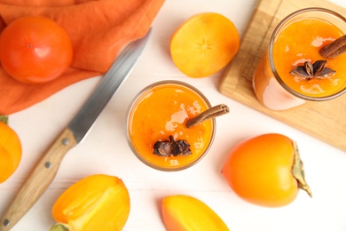 Tasty persimmon smoothie with anise and cinnamon on white wooden table, flat lay