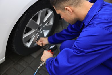 Professional mechanic inflating tire at car service, closeup