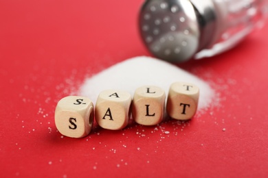 Photo of Word SALT made with cubes on red background, closeup