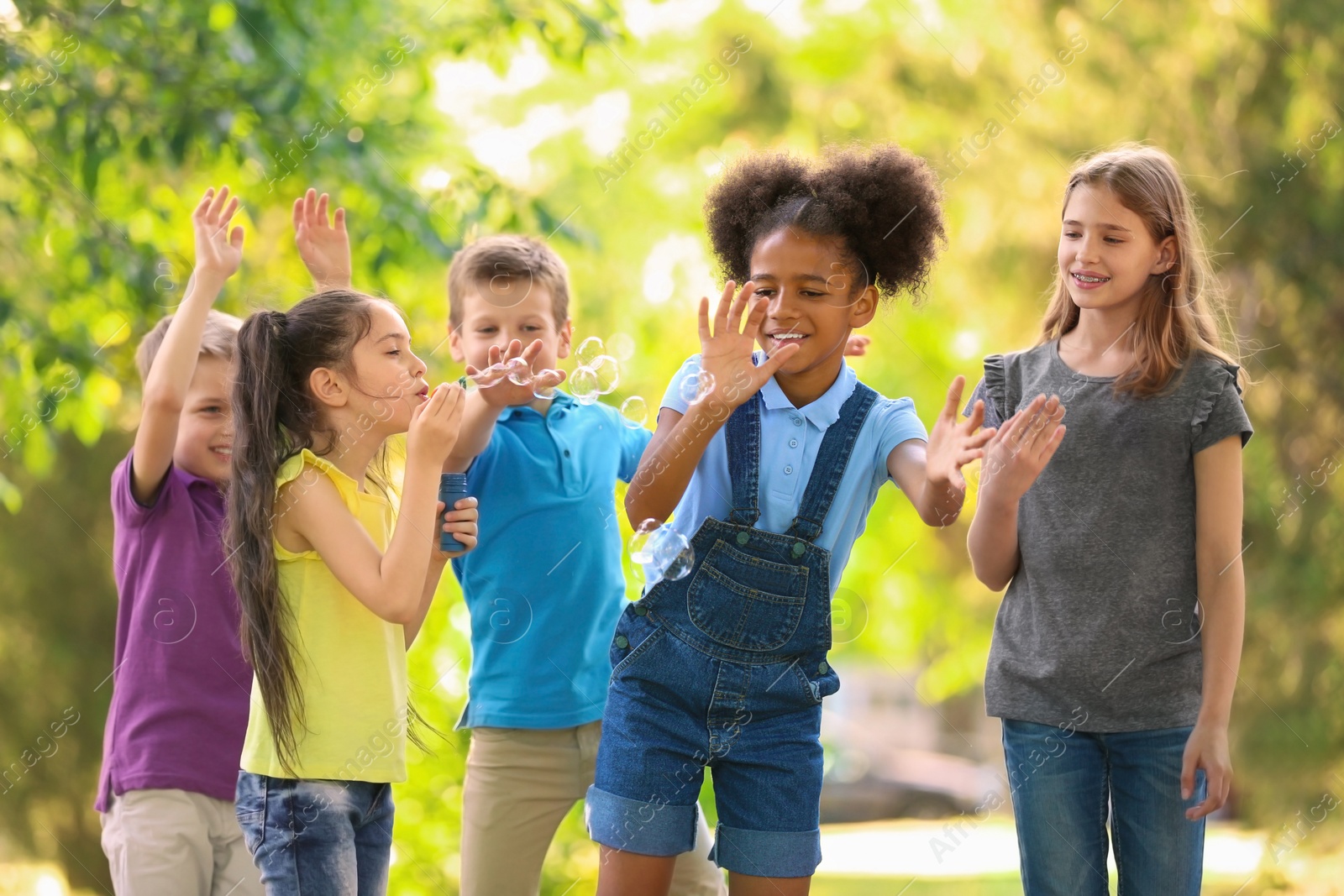 Photo of Cute little children playing with soap bubbles outdoors on sunny day