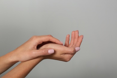 Woman with wet hands on grey background, closeup. Spa treatment