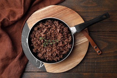 Photo of Fried ground meat and thyme in frying pan on wooden table, top view