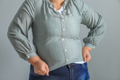 Photo of Overweight woman in tight shirt on light grey background, closeup