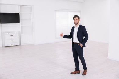 Photo of Happy real estate agent showing thumb up in new apartment