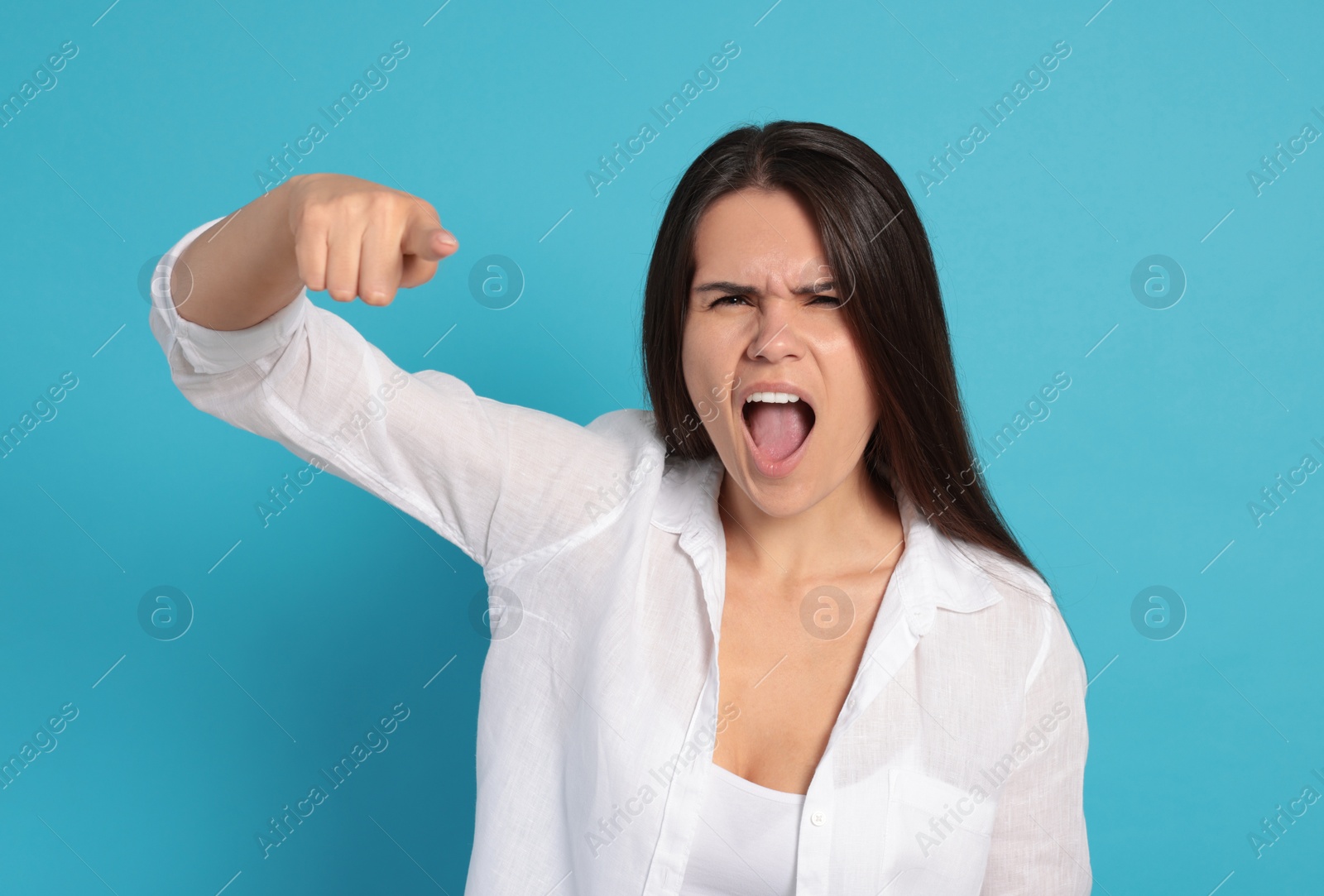 Photo of Aggressive young woman pointing on turquoise background