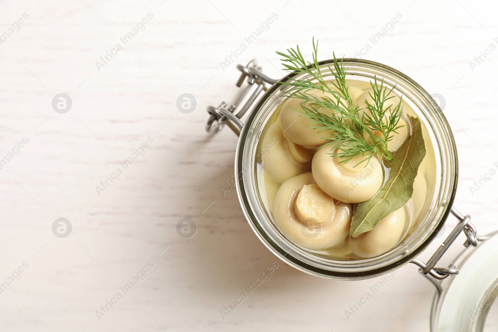 Photo of Jar with marinated mushrooms and dill on white wooden table, top view. Space for text