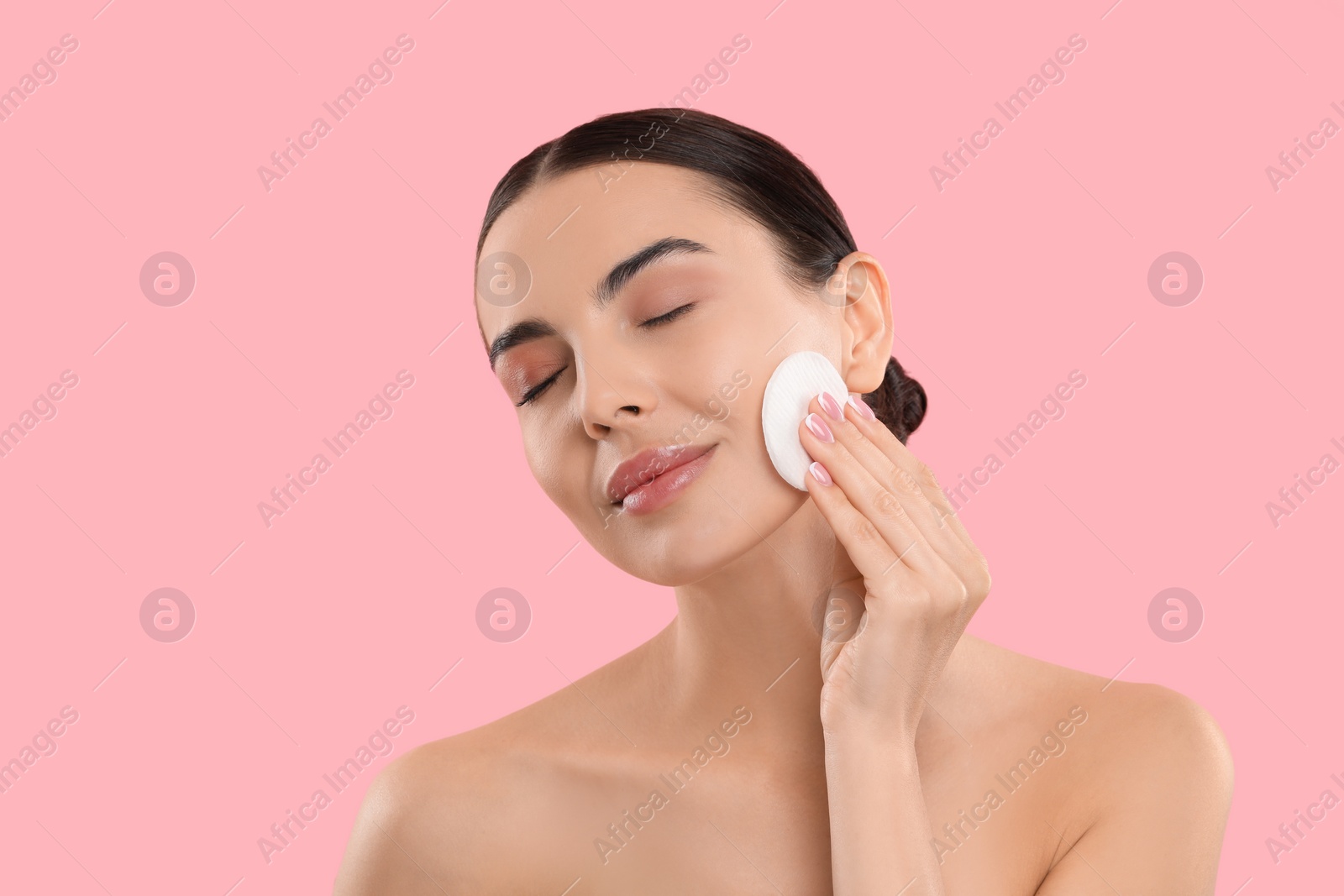 Photo of Beautiful woman removing makeup with cotton pad on pink background. Space for text