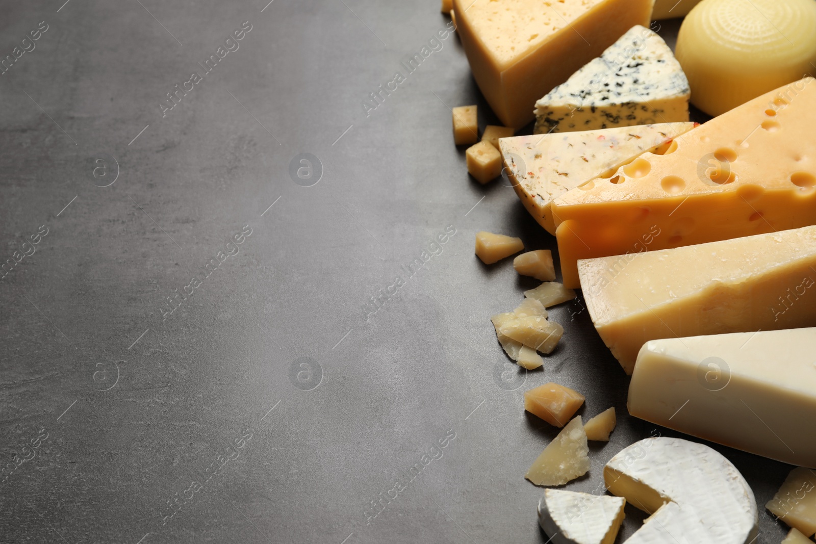 Photo of Different delicious cheeses on grey table, space for text