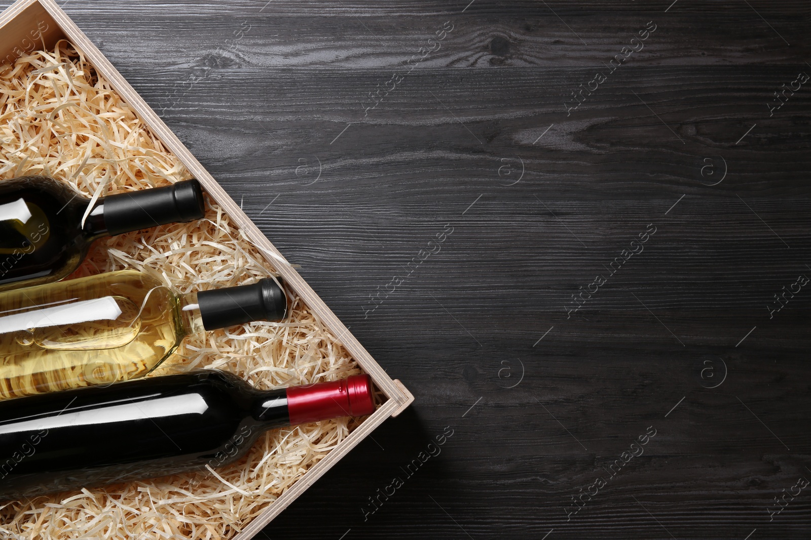 Photo of Wooden crate with bottles of wine on grey table, top view. Space for text