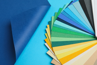 Photo of Color palette and bright paper on light blue background, top view