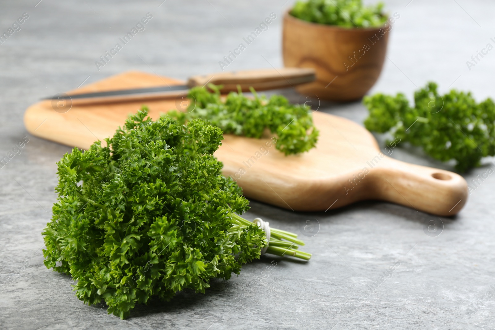 Photo of Bunch of fresh curly parsley on grey table