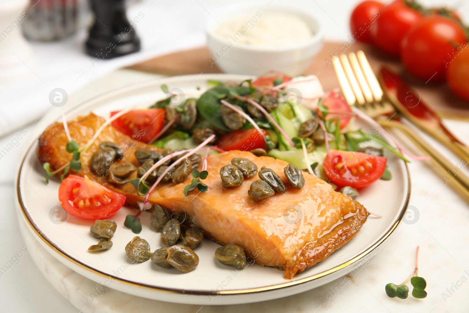 Photo of Delicious salmon with salad and capers on white table, closeup