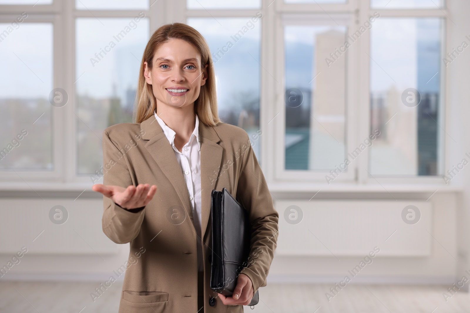 Photo of Happy real estate agent with leather portfolio indoors. Space for text