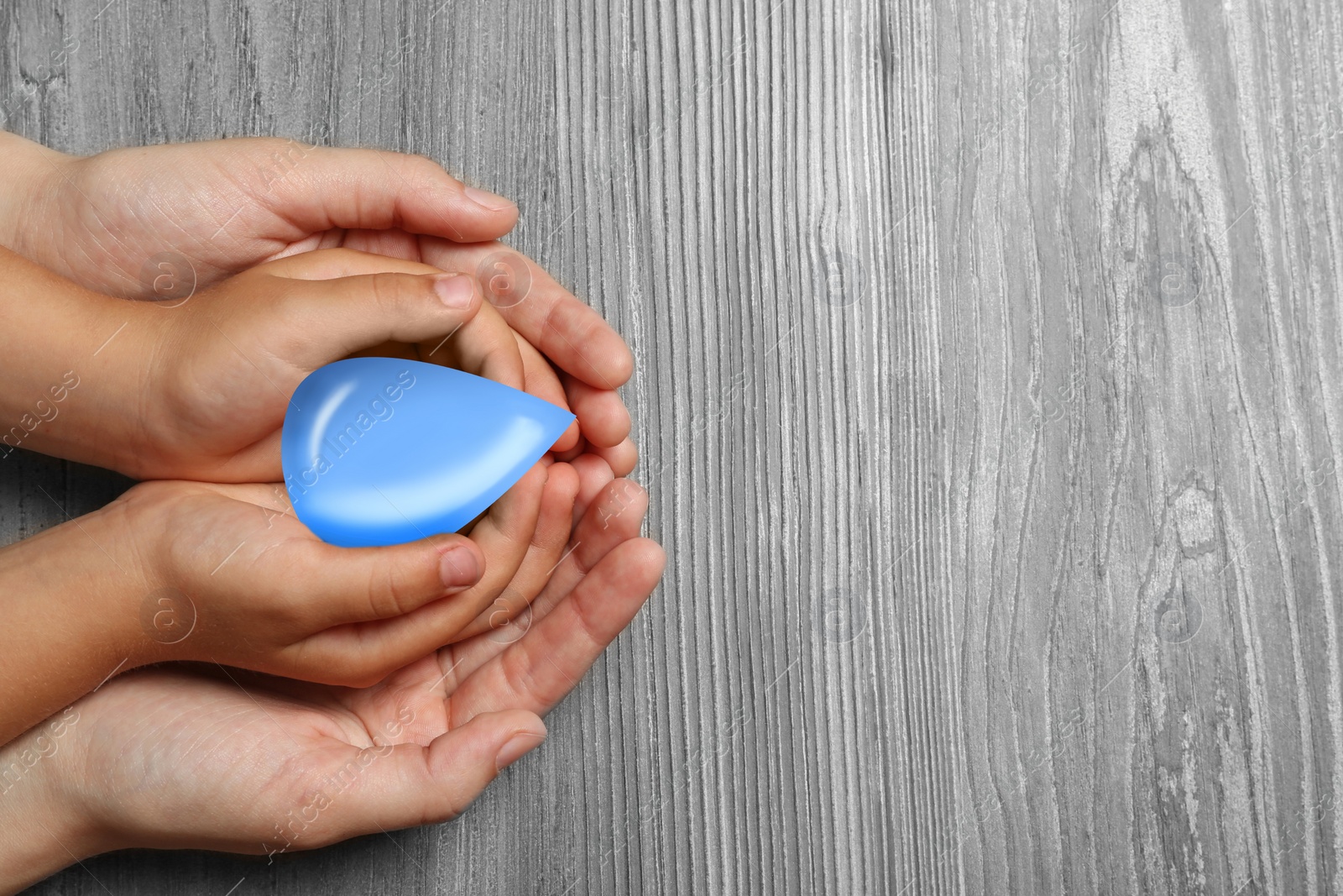 Image of Woman and her child holding water drop on wooden background, top view with space for text. Ecology protection