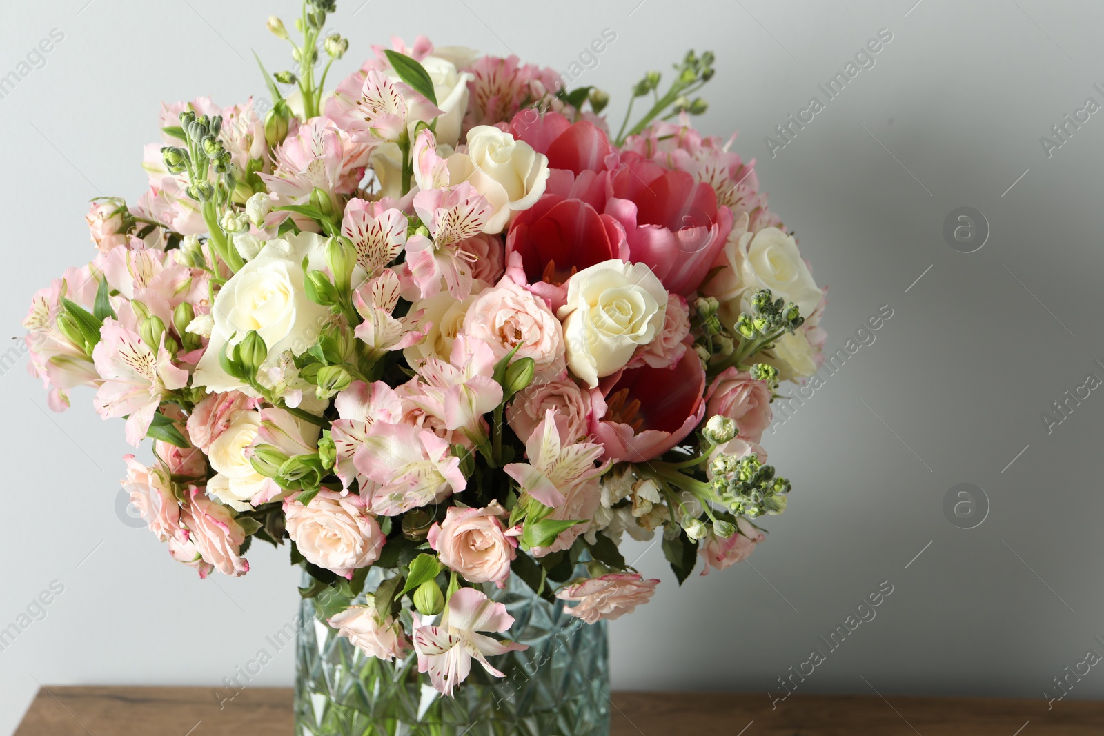 Photo of Beautiful bouquet of fresh flowers in vase on wooden table