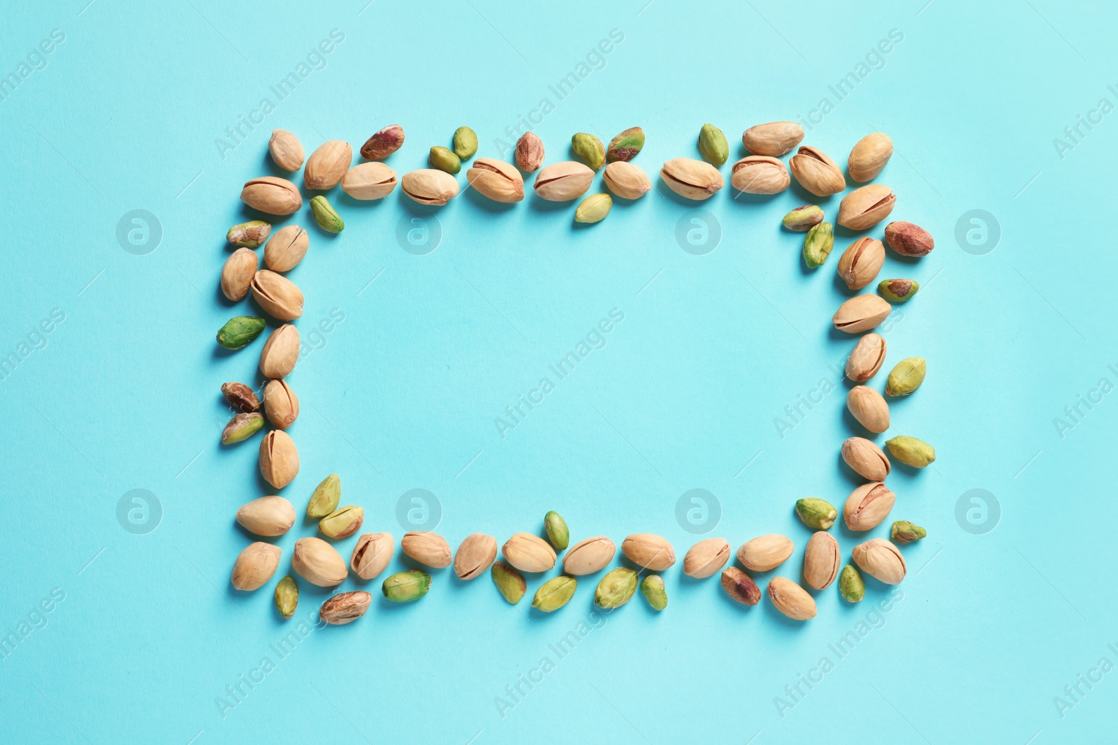 Photo of Frame made of organic pistachio nuts, flat lay. Space for text