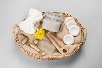 Spa gift set with different products in wicker basket on light grey background, top view